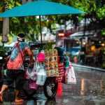 Reiziger houdt regenschirm vast in regen, bescherming tegen natte bagage en slecht weer