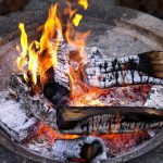 Stilvolle Feuerschale aus Cortenstahl mit rostfarbener Patina als Mittelpunkt eines gemütlichen Gartenbereichs